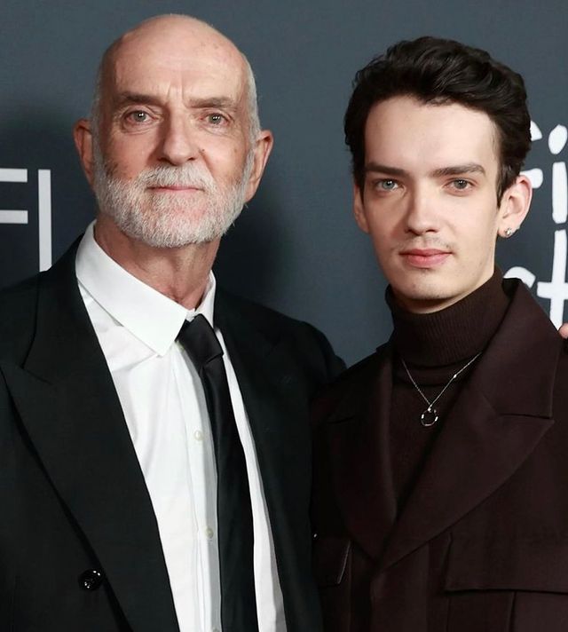 Andy McPhee in a white shirt and black coat with his son in a dark brown dress and a silver locket.